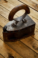 vintage old rusty iron on a bright wooden table next to a black wall