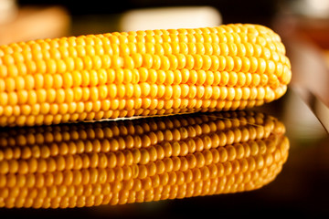 yellow sweet corn grain and a cob in the background.