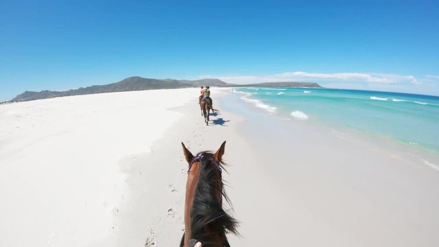 Following horse riders on beach, POV
