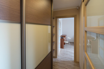 Interior of the flat. Warm tones, wooden floor. Built-in wardrobe