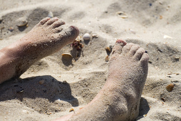 Children's feet covered with sea sand