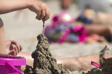 Child's hand builds a sand castle