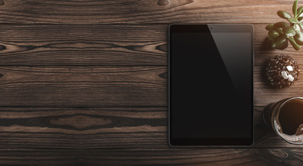 Modern digital tablet with coffee cup, chocolate biscuit and green plant on a wooden desk. Top...