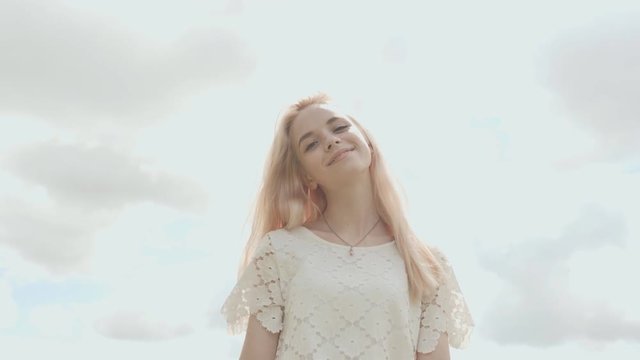 Young Russian girl blonde posing against a white sky on a summer day.