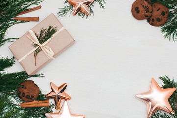 Christmas composition. Christmas gift with cookies, star toys, cinnamon and fir branches on wooden white background. Flat lay, top view, copy space