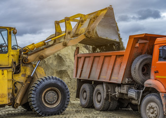 Wheel loader excavator with backhoe unloading clay. beautiful storm clouds,