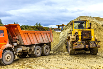 Gravel pit excavation site on a cloudy day with industrial machines. beautiful storm clouds,