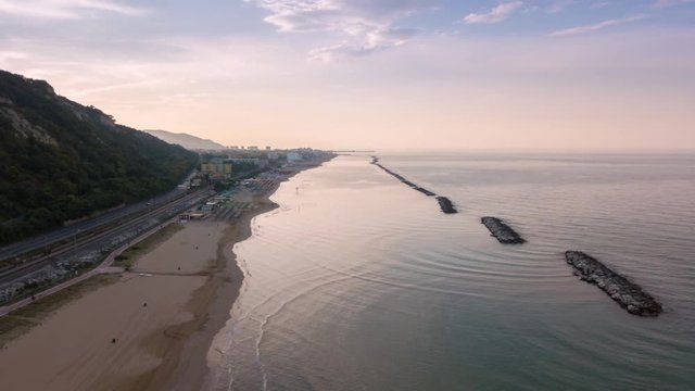Drone Hyperlapse- aerial view of mountain with national road, railway line and moving train, cycle path, beach and sea near Pesaro Town