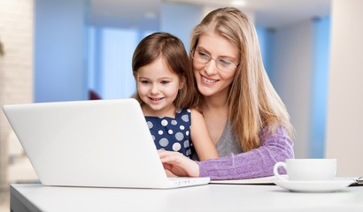 Fototapeta na wymiar Beautiful mother and cute daughter using laptop
