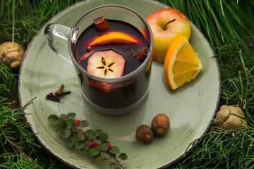 Hot mulled wine in a cup with ingredients to cook on plate.