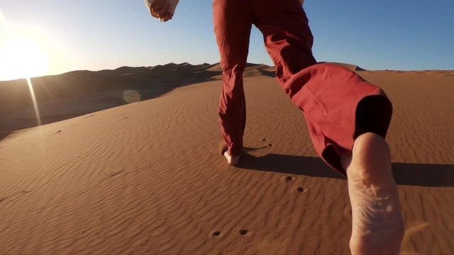 Person runs on sand in desert, slow motion