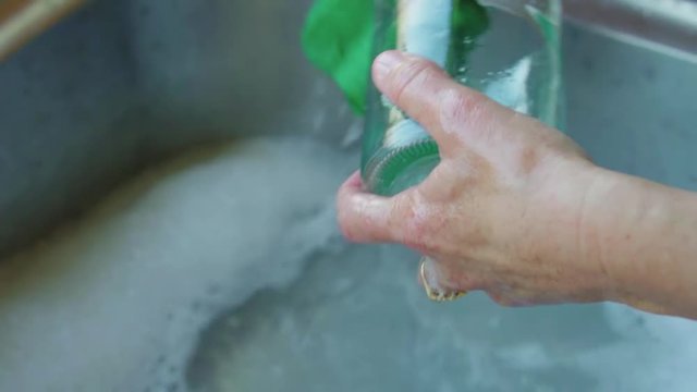Woman washing an empty jar in kitchen sink