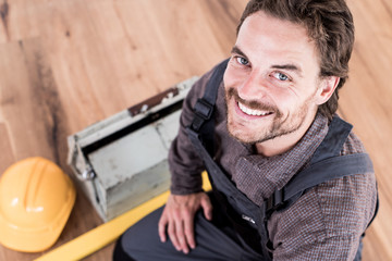 Handwerker lächelnd mit Werkzeug in einem modernen Wohnraum 