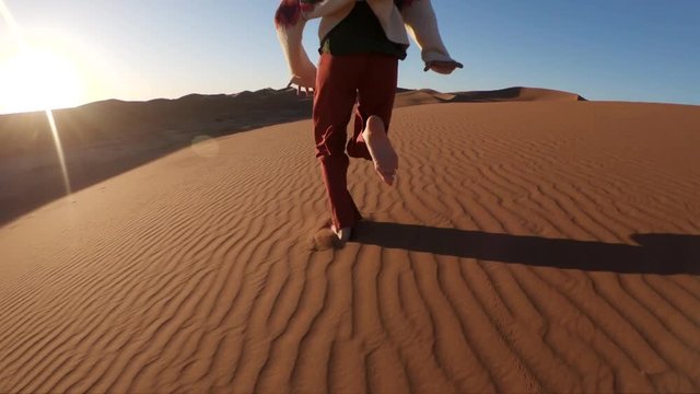 Slow motion, person runs on sand in desert