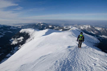 Fototapeta na wymiar Man hiking in Polish Western Tatra mountains during sunny day in winter.