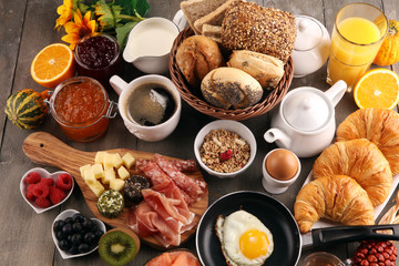 breakfast on table with bread buns, croissants, coffe and juice.