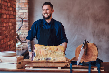 Laughting chef standing near a table with exclusive jerky meat in kitchen with loft interior.
