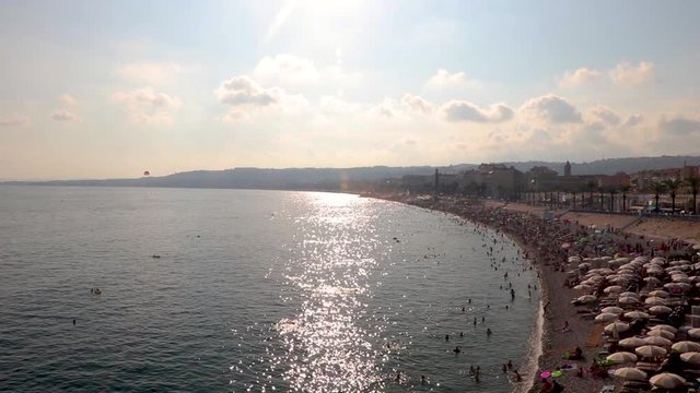 Beach and Promenade des Anglais in Nice, southern France. Scene of the 2016 terrorist attack. Sun reflects in the water. Establishing shot.