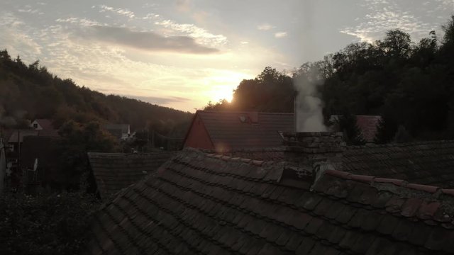 The chimney on the roof of a family house smokes.