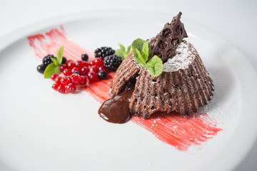 Chocolate fondant with berries and mint on the white plate