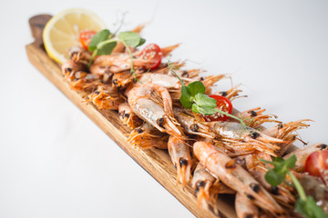 Lots of shrimps on the wooden board with lemon