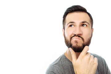 Portrait of brooding bearded man in grey t-shirt looking up and putting hand on face isolated on white background