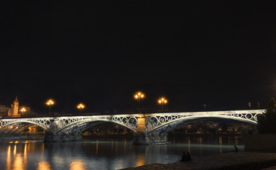 Night view of the Triana bridge, in Sevilla, Andalusia, Spain.
