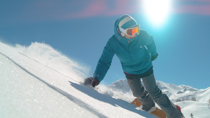 Fototapeta na wymiar SLOW MOTION: Girl snowboarder riding fresh powder snow in backcountry mountain