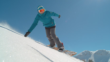 SLOW MOTION: Girl snowboarder riding fresh powder snow in backcountry mountain