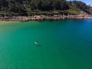  The aerial view of unrecognizable people rises paddle boarding on the surface of the water for sport, and fun. Enjoy the summer SUP activity for holidays.
