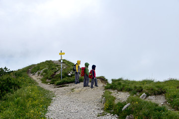 Three young children with backpacks and waterproof jackets ready for adventure on a hiking trail.