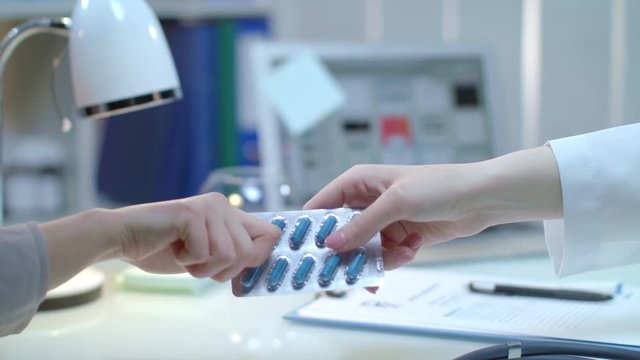 Doctor prescription drugs for patient. Close up of doctor hand giving medicine tablet. Medical treatment. Medical prescription drug pills. Nurse giving medication. Patient health care industry