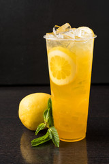 Iced lemonade with mint, lemon slices, and lemon on dark wood table