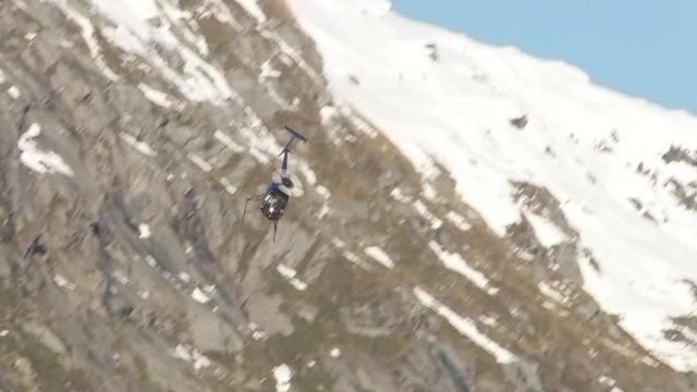 Helicopter loops and heads towards camera in mountain valley