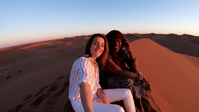 Friends on top of sand dune at sunset, POV