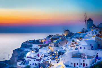 Naklejka premium Traveling Concepts. Panoramic View of Famous Old Town of Oia or Ia at Santorini Island in Greece. Taken During Blue Hour with Traditional White Houses and Windmills.