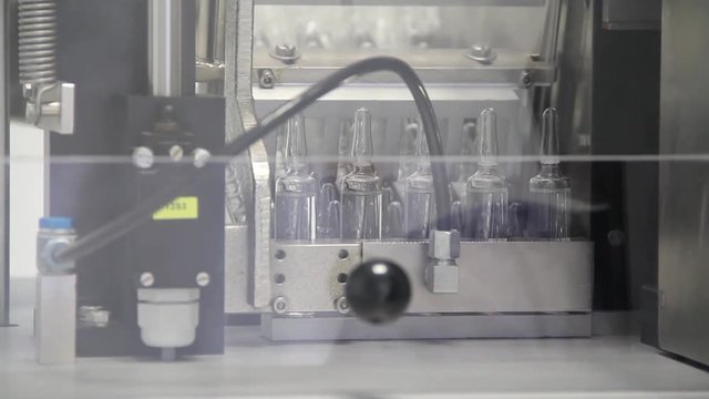 Small batches of medicinal vials being transported and checked for flaws in a machine.