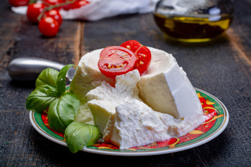 Italian soft cheese, young white ricotta cheese served with fresh basil and tasty ripe cherry tomatoes