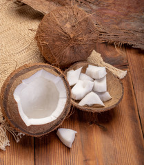 Big tropical palm nut coconut and coconut pieces ready to eat on wooden background close up