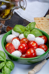 Italian soft cheese, young small balls mozzeralla cheese salad served with fresh basil, tasty ripe cherry tomatoes and Italian olive oil