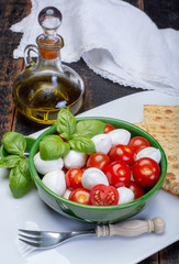 Italian soft cheese, young small balls mozzeralla cheese salad served with fresh basil, tasty ripe cherry tomatoes and Italian olive oil