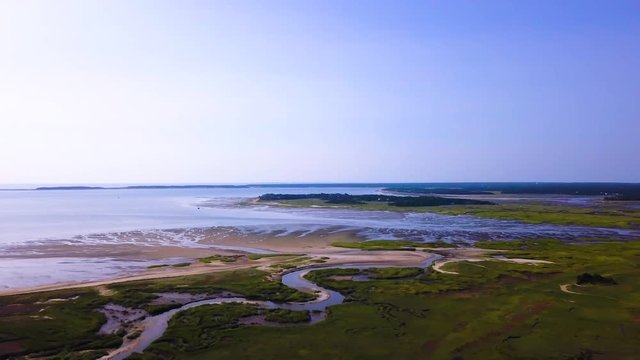 The camera flies over the bay side of Cape Cod, at Sunken Meadows. You can see the marsh and channels of water running through it out to the bay. The camera pans to the right.