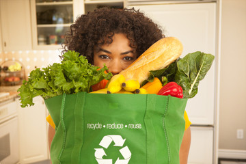 Closeup portrait of millennial black woman carrying big bag of groceries at home