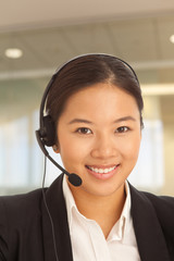Cute millennial female telemarketer smiling at work inside office building