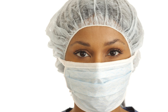 Close Up Of Female Surgeon Wearing Mask And Hair Net On White Backdrop