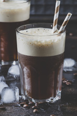 Cold frappe coffee with ice and foam in large glasses on brown background, selective focus