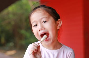 Close up little Asian child girl eating meatballs.
