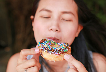 Naklejka premium Close up Asian woman eating rainbow donut.