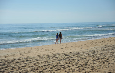 2 teenage girls walk along the beach