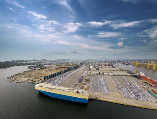 Obraz premium Aerial view of logistics concept commercial vehicles, cars and pickup trucks waiting to be load on to a roll-on/roll-off car carrier ship at Laem Chabang dockyard in Chonburi Province, Thailand